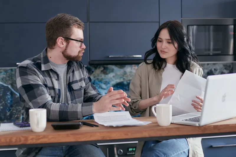 Two people comparing options on a laptop at home