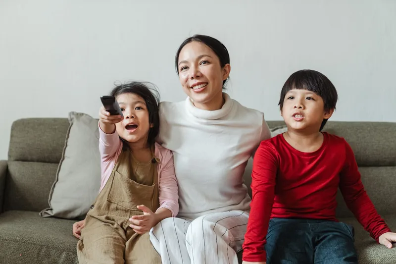 A parent and two children watching television together